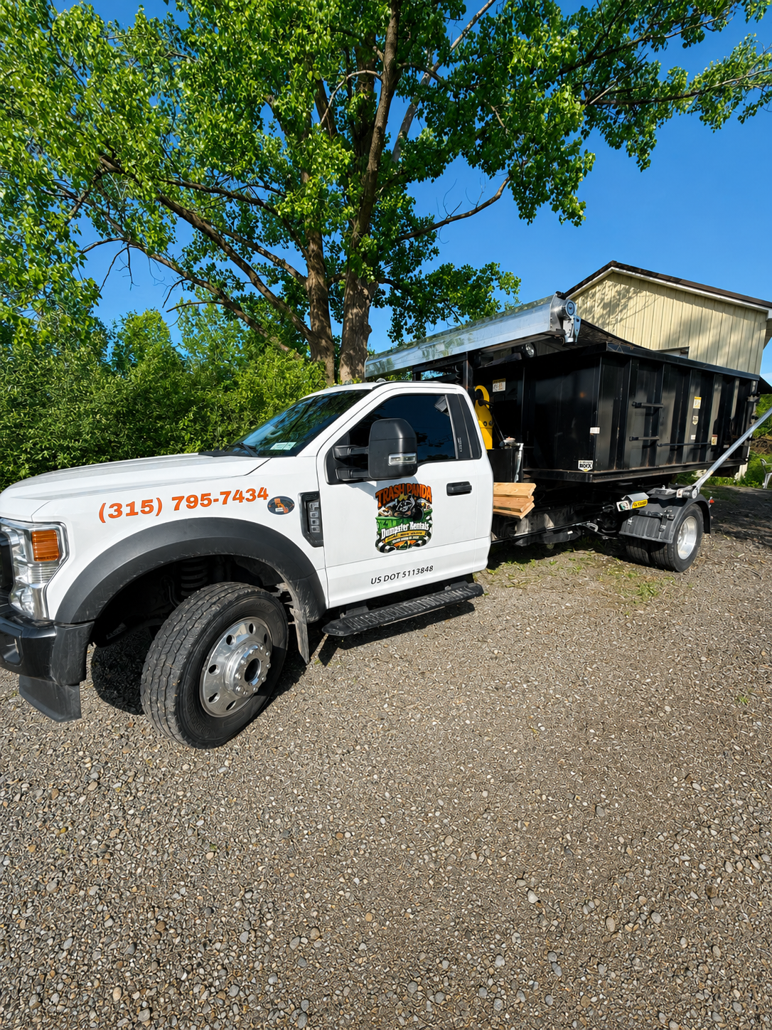 Trash Panda roll-off truck delivering a dumpster